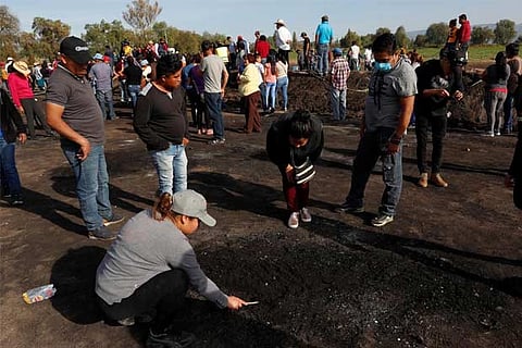 Residents search for human remains  at the site where a pipeline ruptured by oil thieves exploded