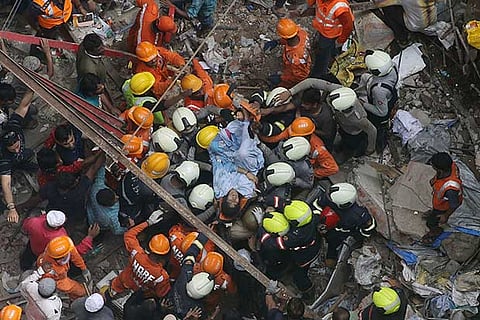 Rescuers carry out a survivor from the site of a building that collapsed in Mumbai.