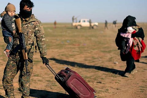A fighter from Syrian Democratic Forces (SDF) holds a baby near the village of Baghouz, Deir Al Zor
