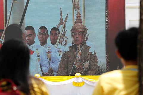 People watch a screening of King Maha Vajiralongkorn being crowned during his coronation in Bangkok