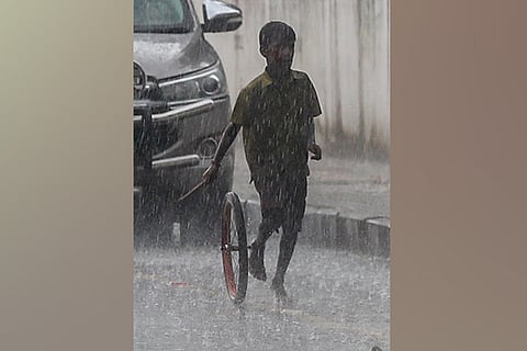 A boy plays with his wheel unperturbed by the heavy downpour in Chepauk on Tuesday evening.