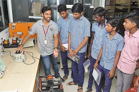 An engineering student explains a model to school kids at the expo