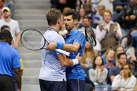 Novak Djokovic (right) embraces Stan Wawrinka after conceding the match in the third set of fourth round
