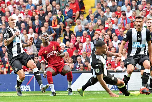 Sadio Mane (in red) curls a ball past the Newcastle United defence