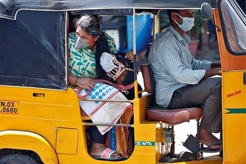 A dog wearing a protective mask is seen with its owner inside an autorickshaw | Reuters