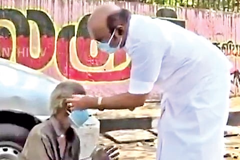 Fisheries Minister D Jayakumar helps an octogenarian wear a mask in Royapuram, Chennai, on Thursday