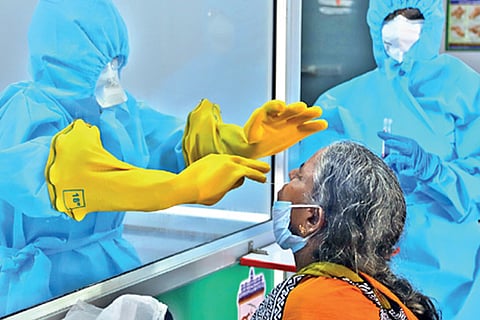 Medical professionals take swab samples from a woman at Pudupet
