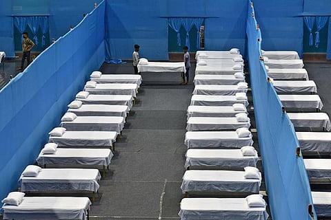 Workers install beds to set up a quarantine facility inside a sports Complex in Guwahati