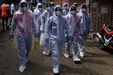 Healthcare workers walk towards a check-up camp for the coronavirus disease in Mumbai