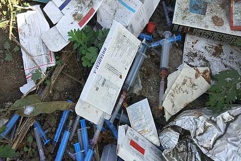 Waste, including syringes, tablets, along with bills, can be found among the disposed waste