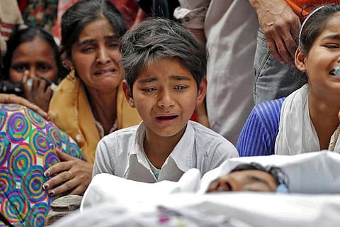 People mourn next to the body of Muddasir Khan who succumbed to his injuries in the Delhi riots