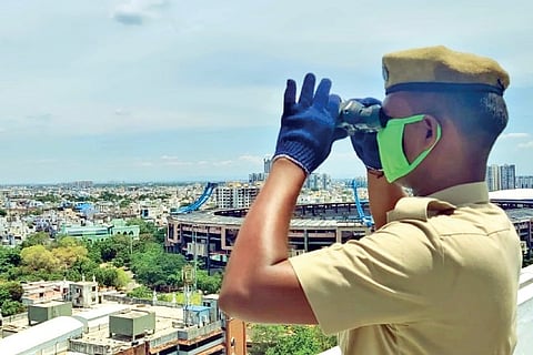 A policeman with binoculars on the terrace of suburban train terminal at Central