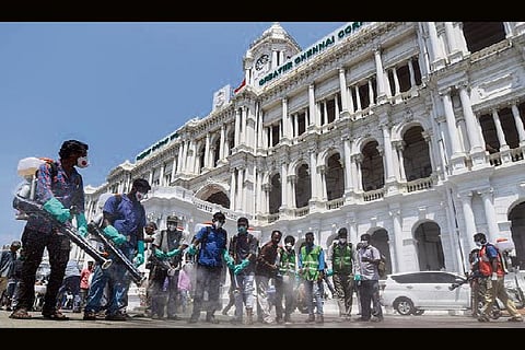 Municipal workers spray disinfectants around the building premises of Chennai Municipal Corporation