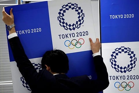 A staff takes out a banner featuring Tokyo 2020 Olympics emblem from the wall after a news conference