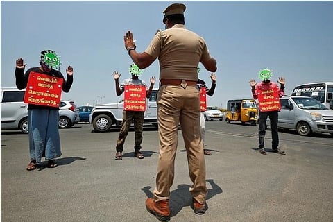 People wear masks depicting coronavirus and placards | Reuters