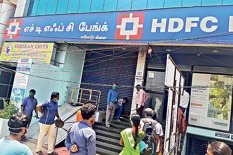 Officials locking a bank and a nearby ATM for ignoring social distancing norms in Erode district