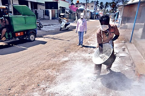 Sanitary workers disinfect a street in a containment zone.