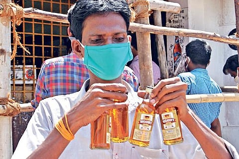 A customer walks away after buying four quarter bottles of liquor from a Tasmac shop in Madurai.