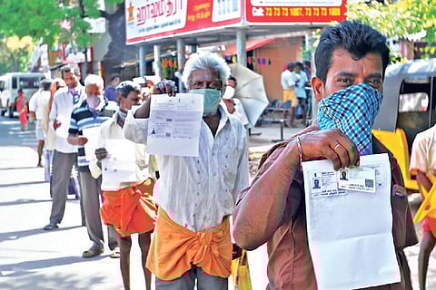 Tipplers waiting in a queue to buy liquor display their identity cards in Tiruchy.