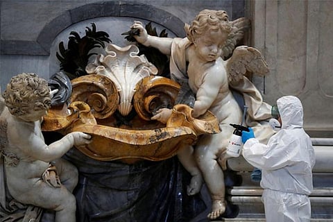 A Vatican staff member in protective gear sanitizes the interior of St. Peter's Basilica (Reuters)