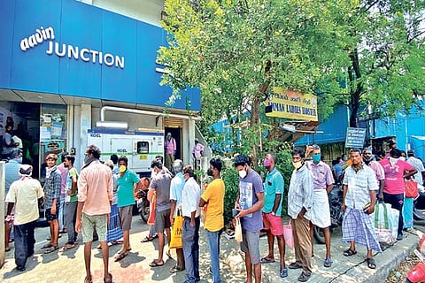 People wearing masks waiting in line outside an Aavin outlet