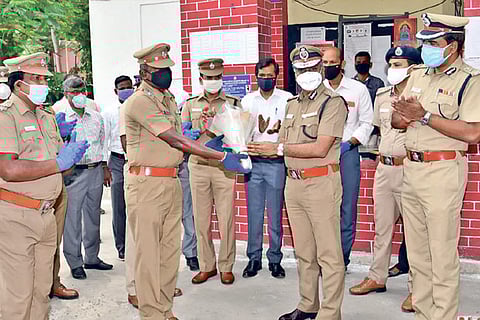 Commissioner AK Viswanathan hands over a bouquet to SI S Arunachalam as other police personnel look