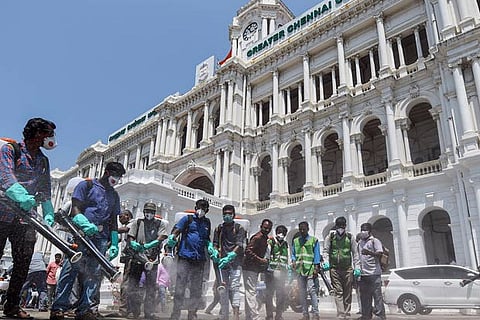 Municipal workers spray disinfectants around the building premises of Chennai Corporation