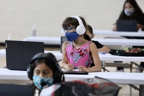 Scared by virus surge, more US schools suspend in-person classes