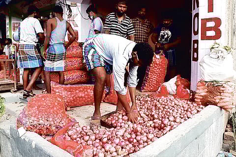 A vendor arranges bags of onions at a market on Tuesday