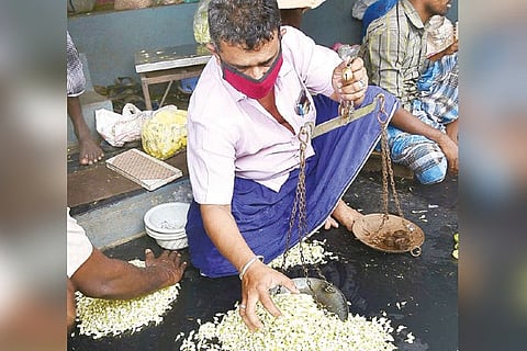 A trader weighing jasmine at Mattuthavani flower market in Madurai on Sunday.