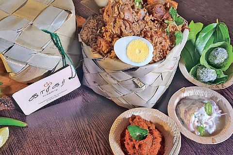 Mutton Karigar perunchoru with special thokku, raita and paan ladoo packed in a palm leaf box
