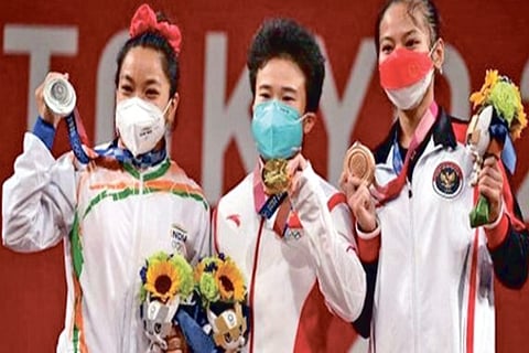 Hou Zhihui of China (C) stands with Mirabai Chanu Saikhom of India (L) and Windy Cantica Aisah (R)