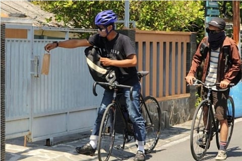 A cyclist delivers medicine at a house (Credit: Reuters)