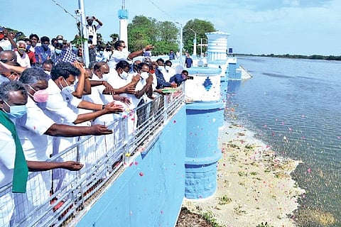 Ministers and farmers shower petals and paddy seeds on the water gushing out from Kallanai
