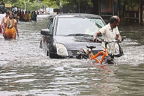 People wade through a flooded road in Chennai