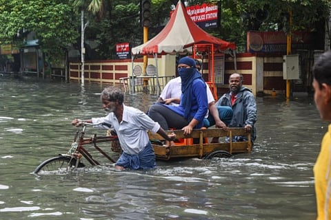 People wading through a flooded road in Chennai