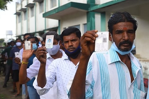 Men wait in a queue to cast their votes in Kovilambakkam on Wednesday