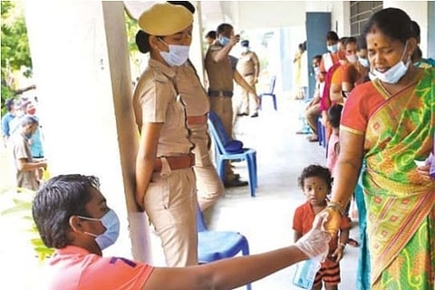 Voters sanitise their hands at a booth in Kovilambakkam