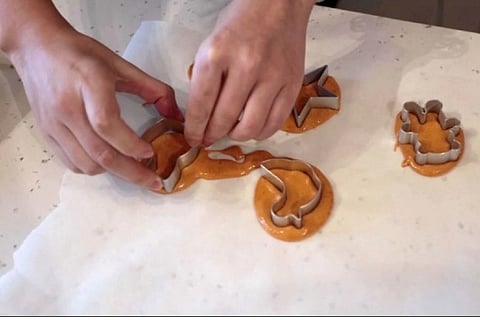 A customer puts shape templates onto circles of biscuit mix during a session