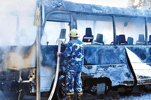 A Syrian firefighter extinguishes the fire on the bus at the site of an explosion, in Damascus