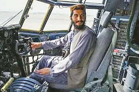 Taliban fighter sits in the cockpit of an Afghan Air Force aircraft at the airport in Kabul