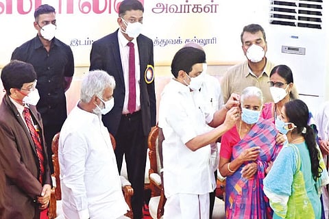 Chief Minister Stalin help an elderly woman fix her hearing aid after handing over the same to beneficiaries