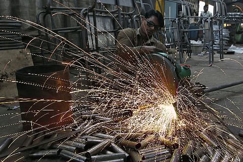 A worker cuts a metal pipe inside a steel furniture production factory (Credit: Reuters)