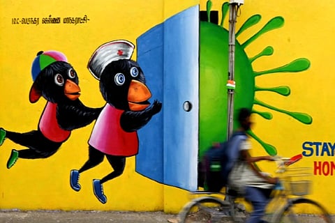 A girl rides a bicycle past a Covid-19 coronavirus awareness mural (Credit: AFP)