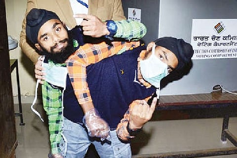 Conjoined twins Sohna and Mohna show their ink marked fingers after casting their votes