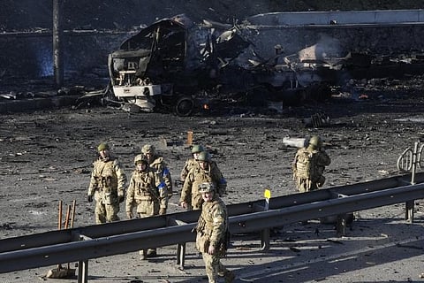 Ukrainian soldiers walk past debris of a burning military truck on a street in Kyiv (AP)