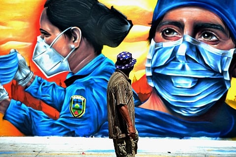 A man looks at a mural depicting a health worker and a police officer (Credit: AFP)