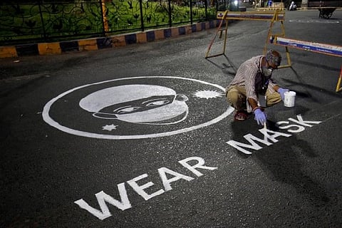 A man draws an awareness message on a road about wearing mask (Credit: Reuters)