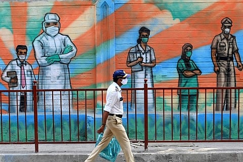 A police officer walks past a mural depicting frontline Covid-19 warriors (Credit: AFP)