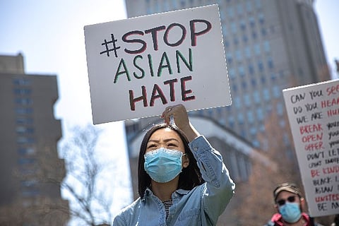 A protester carrying a placard "Stop Asian Hate". Image courtesy: Reuters